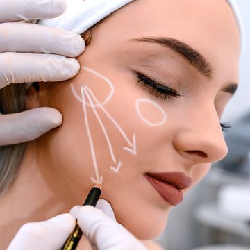 beautician draw correction lines on woman face