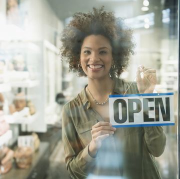 Black woman holding open sign in store window black woman holding open sign in store window