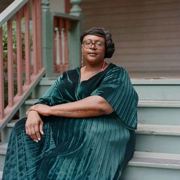 oriaku njoku sitting on steps outside a house wearing a teal outfit