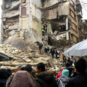 onlookers watch as rescue teams look for survivors under the rubble of a collapsed building after an earthquake in the regime controlled northern syrian city of aleppo on february 6 2023