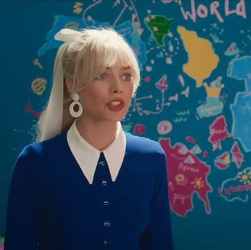 margot robbie as barbie standing in front of a doodled and inaccurate world map in the barbie film